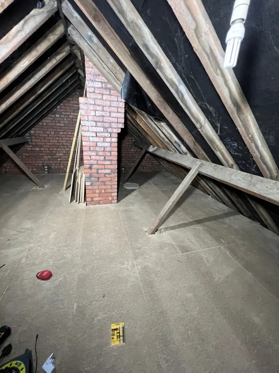 A loft floor fully boarded around a brick chimney breast and roof struts